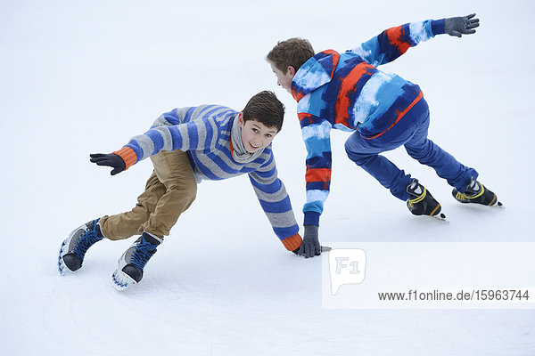 Zwei Jungen laufen Schlittschuh auf einem gefrorenen See