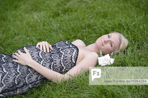 Young pregnant woman lying on a meadow