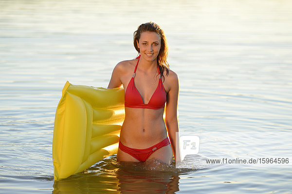 Young woman with airbed in a lake