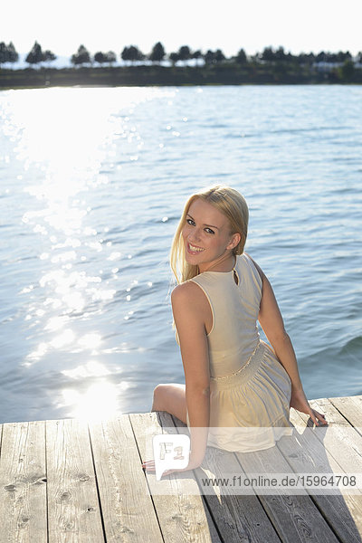 Young blond woman on a jetty at a lake  Styria  Austria