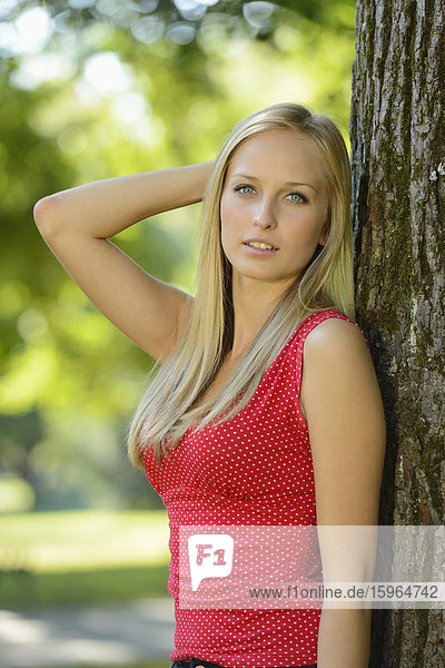 Young blond woman at a tree trunk in a park