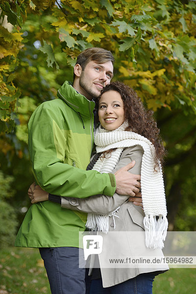 Lächelndes Paar umarmt sich im Herbst