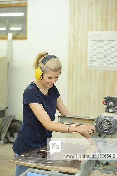 Junge Frau arbeitet in einer Schreinerei an einer Kreissäge