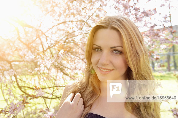 Junge Frau an blühendem Kirschbaum  Portrait