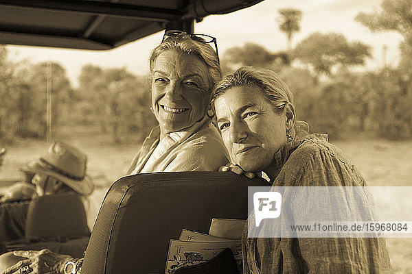 Ältere Frau und reife Tochter  zwei Generationen von Frauen in einem Safarijeep lachend.
