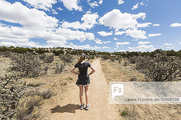 Rear view of 14 year old girl looking at dirt road  Galisteo Basin  NM.