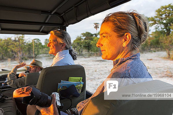Ältere Frau und reife Tochter  zwei Generationen von Frauen in einem Safarijeep mit Blick auf den Sonnenuntergang.