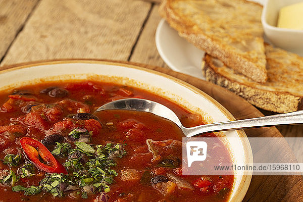 Nahaufnahme einer Tomaten- und Gemüsesuppe mit Beilage von Brot in einem Cafe.