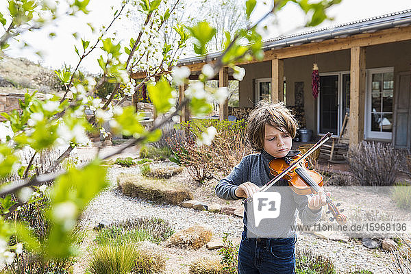 6 year old boy playing violin outside of his home