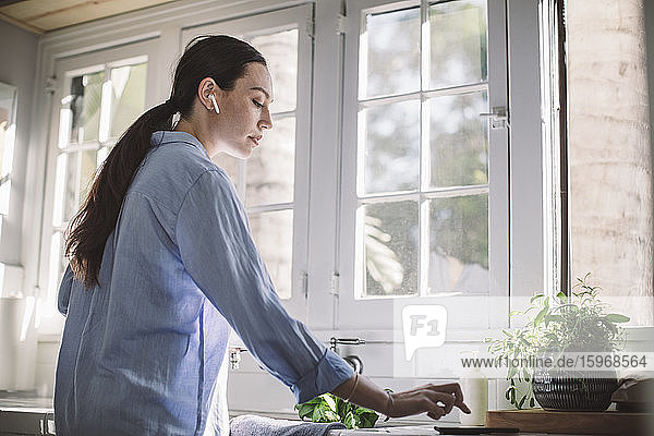 Seitenansicht einer Geschäftsfrau  die ein Smartphone auf der Küchentheke im Heimbüro benutzt
