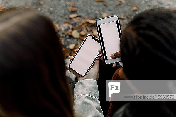 High angle view of teenage girls using social media on smart phones