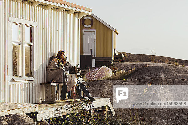 Sohn zeigt auf die Mutter  während er an einem sonnigen Tag vor der Kabine sitzt