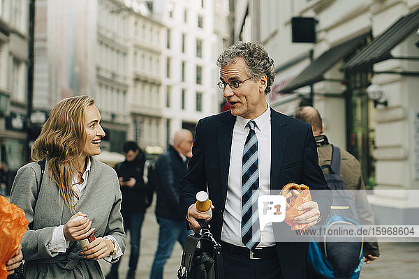 Geschäftsmann und Geschäftsfrau mit Essen zu Fuß in der Stadt