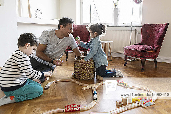 Spielerische Bindung der Tochter an den Vater  während der Bruder im Wohnzimmer spielt
