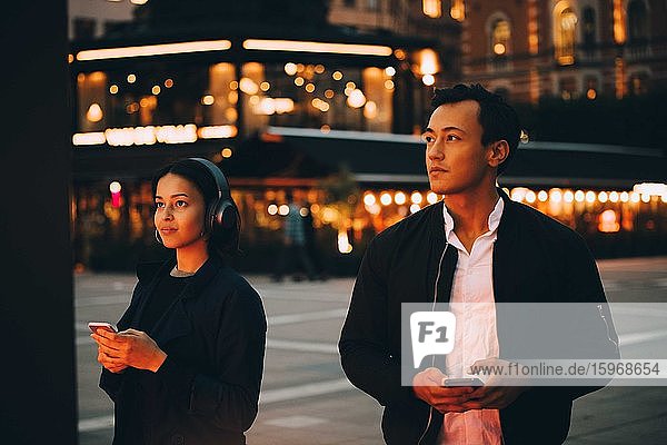 Mann und Frau benutzen Netz  wenn sie nachts in der Stadt stehen
