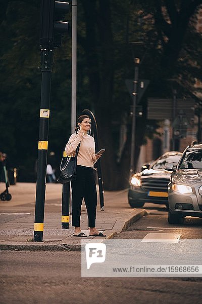 Modische Frau mit Telefon auf einem Fußweg in der Stadt