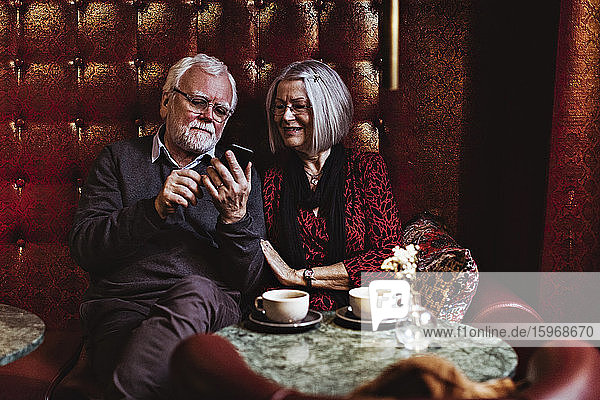 Älterer Mann benutzt ein Smartphone  während er mit seinem Partner im Hotel sitzt