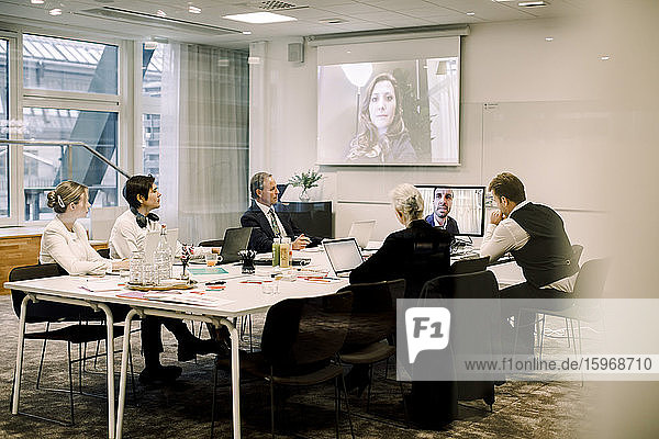 Männliche und weibliche Fachkräfte im Sitzungssaal während einer Webkonferenz im Büro
