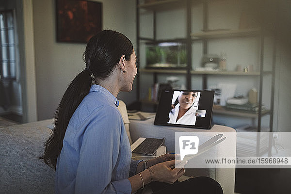 Seitenansicht eines Architekten mit Stoffmuster  der sich per Laptop per Videokonferenz bei der Arbeit zu Hause unterhält