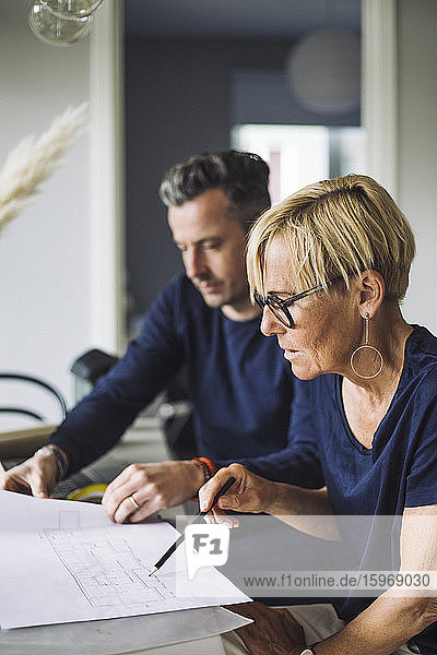 Woman and man discussing blueprint working at home
