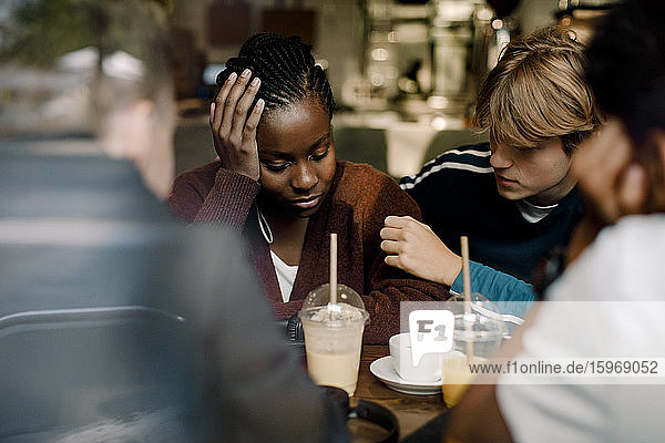 Teenager Junge tröstet Freundin  während er durch Glasfenster im Café sitzt