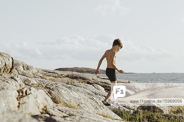 Shirtless boy walking on archipelago during weekend