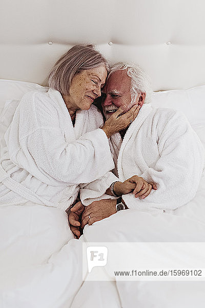 Smiling romantic senior couple on bed in hotel room