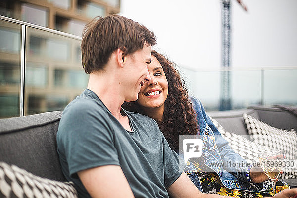 Lächelnder Mann mit Partnerin auf der Terrasse beim geselligen Beisammensein