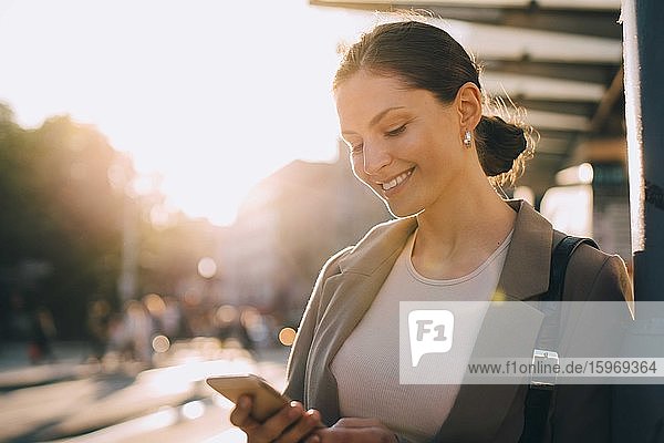 Smiling woman messaging while standing in city