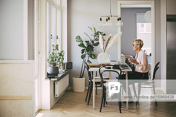 Woman sitting at table having an online meeting working at home