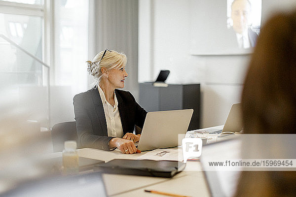 Reife Geschäftsfrau mit Laptop konzentriert sich bei Konferenzsitzung im Sitzungssaal