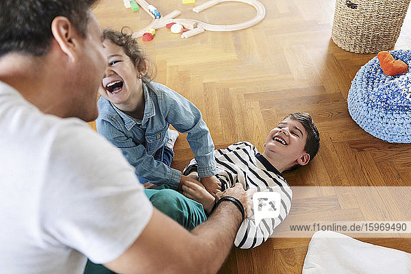 Hochwinkelaufnahme eines Vaters  der zu Hause mit Kindern spielt