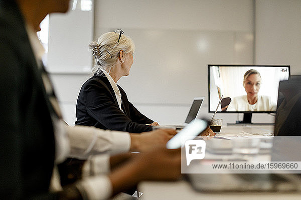 Geschäftsfrau nimmt an Videokonferenz mit Kollegen in Bürobesprechung teil