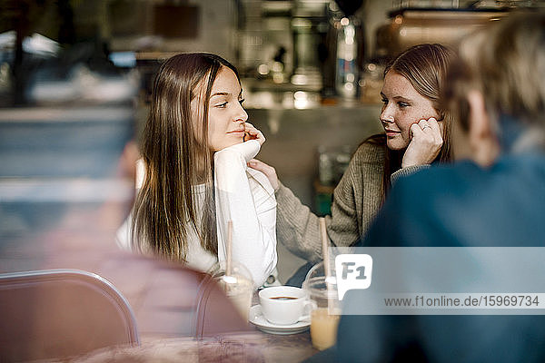 Teenage girl looking at friend while sitting in cafe