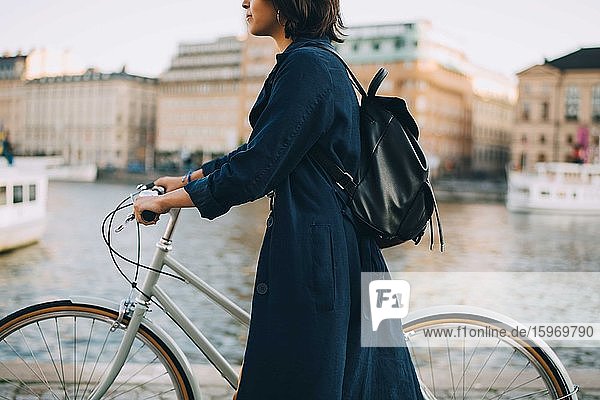 Junge Frau mit Fahrrad überquert Fluss in der Stadt