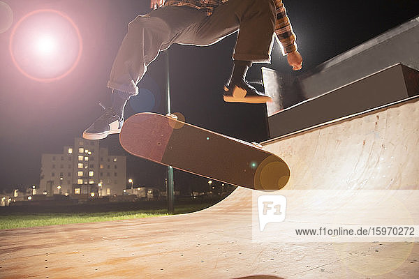 Junger Mann fährt Skateboard auf Rampe im Skatepark
