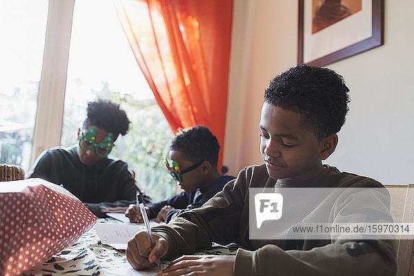 Boy writing Christmas cards at table
