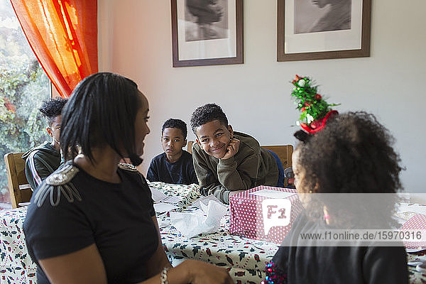 Glückliche Familie packt Weihnachtsgeschenke bei Tisch ein