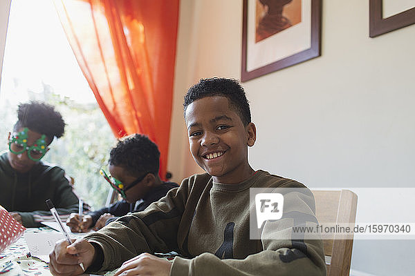 Portrait happy boy writing Christmas cards at table