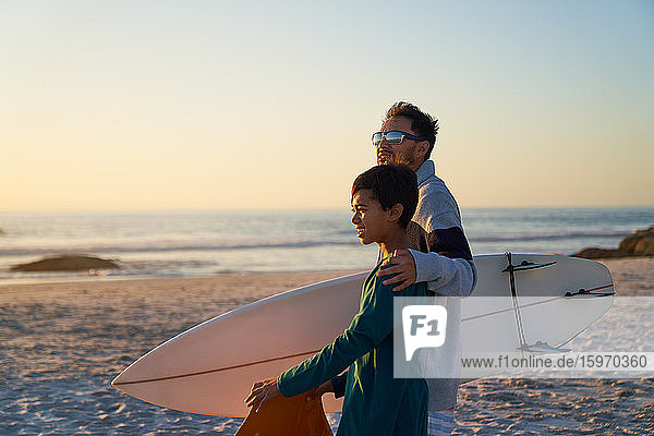 Father and son with surfboard on sunny beach
