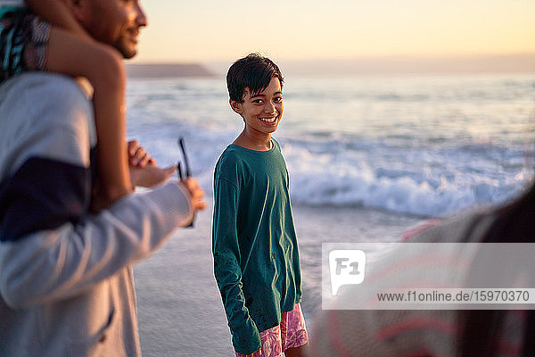 Porträt eines glücklichen Jungen am Meeresstrand mit Familie