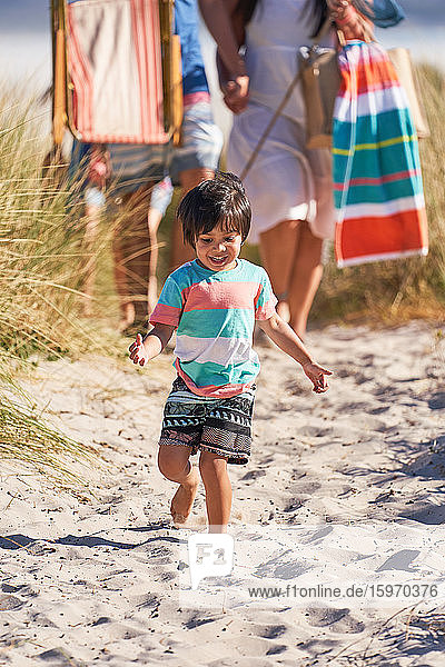 Boy running in sand on sunny beach