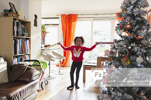 Porträt eines glücklichen Mädchens in Weihnachtspullover mit Geschenkpapier in der Hand