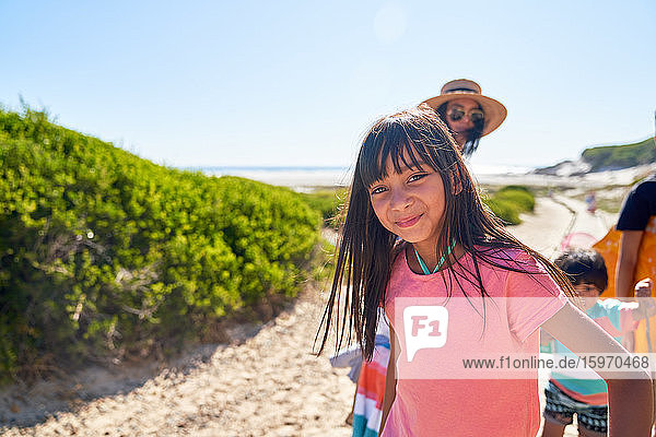 Porträt eines glücklichen Mädchens am sonnigen Strand mit Familie