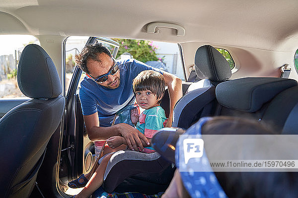Vater befestigt Kleinkind-Sohn im Autositz