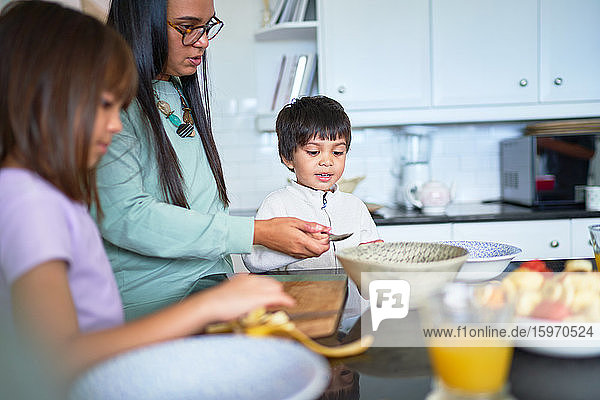 Mutter und Kinder schneiden frisches Obst in der Küche