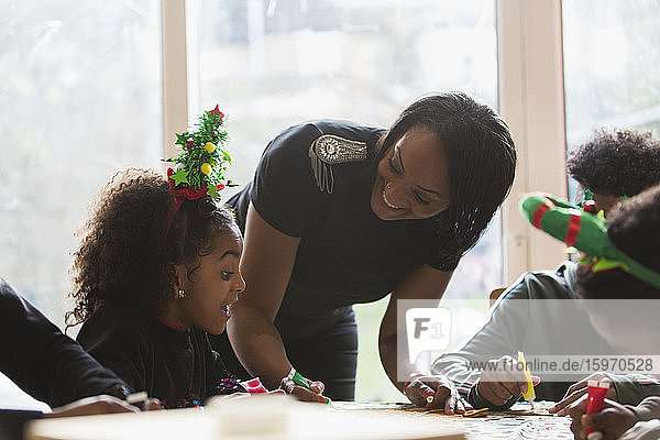 Glückliche Mutter und Tochter schmücken Weihnachtsplätzchen bei Tisch
