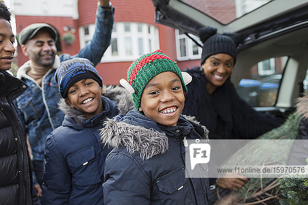 Porträt glückliche Familie beim Verladen des Weihnachtsbaums ins Auto