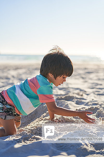 Junge spielt im Sand am sonnigen Sommerstrand