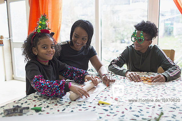 Glückliche Mutter und Kinder backen Weihnachtsplätzchen bei Tisch